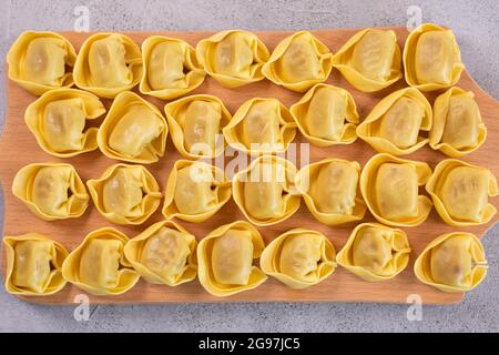Tortelloni non cotti con farcitura di funghi su tavola di legno. Cucina italiana Foto Stock