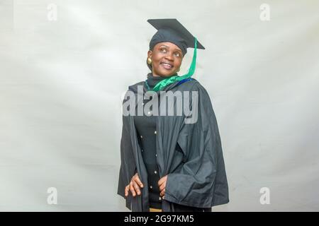 Ritratto di una donna africana felice laureata o laureata studenti sorridenti nel suo vestito nero Foto Stock