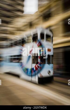 Un tram passa davanti al Pawn, un rinnovato 'tong lau' o edificio dello shopping a WAN Chai, Isola di Hong Kong, in un'inquadratura panoramica con sfocatura selettiva del movimento Foto Stock