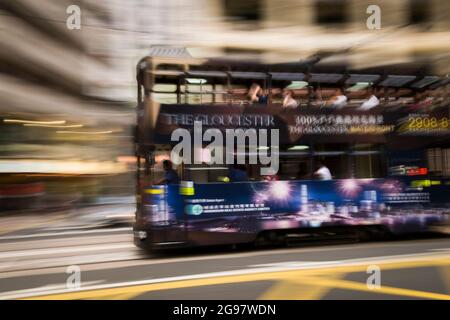 Un tram passa davanti al Pawn, un rinnovato 'tong lau' o edificio dello shopping a WAN Chai, Isola di Hong Kong, in un'inquadratura panoramica con sfocatura selettiva del movimento Foto Stock