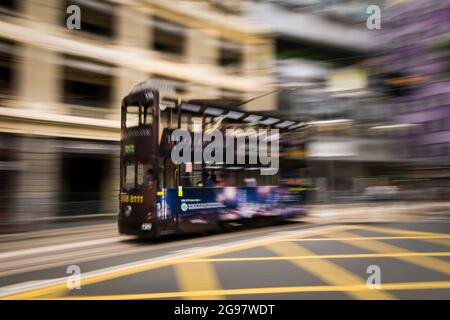 Un tram passa davanti al Pawn, un rinnovato 'tong lau' o edificio dello shopping a WAN Chai, Isola di Hong Kong, in un'inquadratura panoramica con sfocatura selettiva del movimento Foto Stock