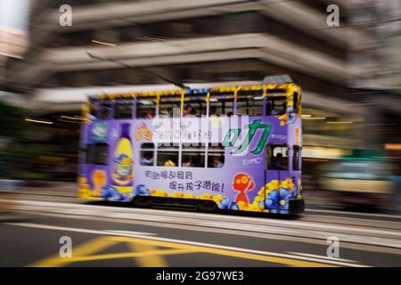 Un tram passa davanti al Pawn, un rinnovato 'tong lau' o edificio dello shopping a WAN Chai, Isola di Hong Kong, in un'inquadratura panoramica con sfocatura selettiva del movimento Foto Stock