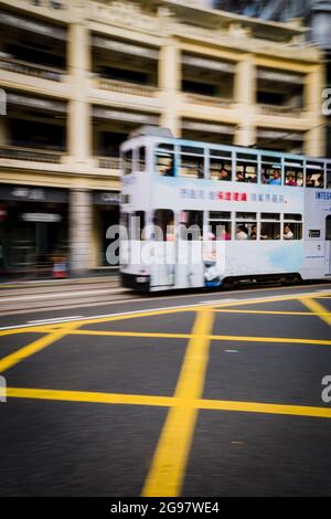 Un tram passa davanti al Pawn, un rinnovato 'tong lau' o edificio dello shopping a WAN Chai, Isola di Hong Kong, in un'inquadratura panoramica con sfocatura selettiva del movimento Foto Stock