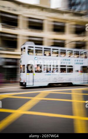 Un tram passa davanti al Pawn, un rinnovato 'tong lau' o edificio dello shopping a WAN Chai, Isola di Hong Kong, in un'inquadratura panoramica con sfocatura selettiva del movimento Foto Stock