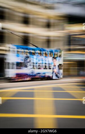 Un tram passa davanti al Pawn, un rinnovato 'tong lau' o edificio dello shopping a WAN Chai, Isola di Hong Kong, in un'inquadratura panoramica con sfocatura selettiva del movimento Foto Stock