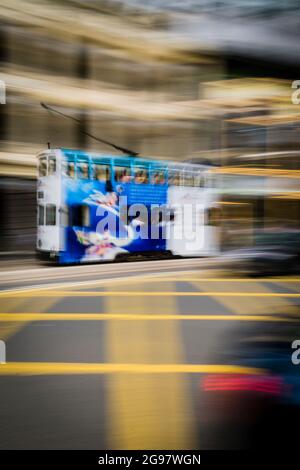 Un tram passa davanti al Pawn, un rinnovato 'tong lau' o edificio dello shopping a WAN Chai, Isola di Hong Kong, in un'inquadratura panoramica con sfocatura selettiva del movimento Foto Stock