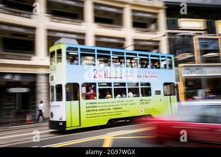 Un tram passa davanti al Pawn, un rinnovato 'tong lau' o edificio dello shopping a WAN Chai, Isola di Hong Kong, in un'inquadratura panoramica con sfocatura selettiva del movimento Foto Stock