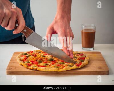 Medellin, Colombia - 1 gennaio 2021: Focaccia barese con pomodori freschi e olive verdi servita su un tagliere di legno di bambù su uno Backgroun bianco Foto Stock