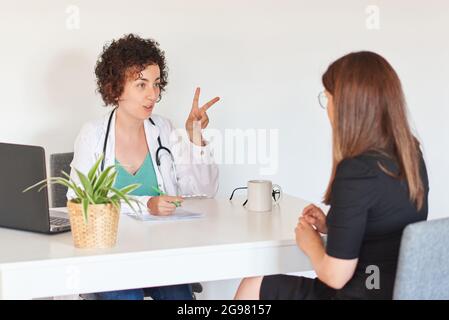 Una dottoressa prescrive alcune pillole ad un paziente nel suo ufficio Foto Stock