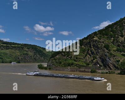 Splendido paesaggio con il fiume Reno circondato da pendii rocciosi con chiatta di carico che passa da e nave da crociera escursione in background in giornata di sole. Foto Stock