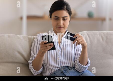 Primo piano focalizzato donna indiana tenendo carta di credito, inserendo le informazioni Foto Stock