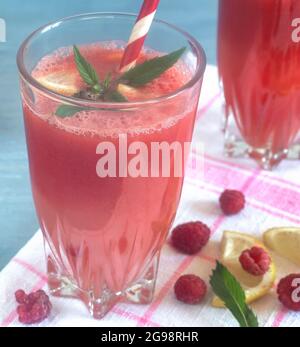 Succo di anguria in un bicchiere con limone e lamponi. Foto Stock