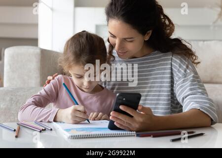 Amorevole disegno di mamma latina e figlia usando la cella Foto Stock