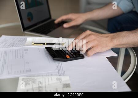 Maschile lavora con il bilancio utilizzando calcolatrice e laptop closeup Foto Stock