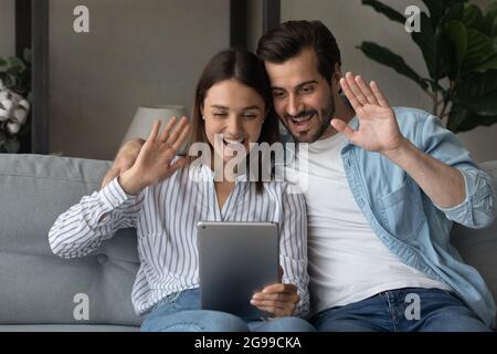 La coppia siede sul divano utilizza il tablet per avviare la conversazione tramite videoconferenza Foto Stock