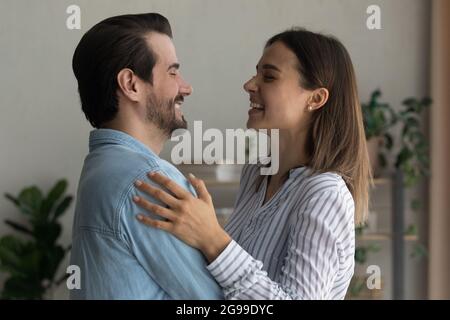 Allegro coniugi in piedi hugging indoor ridere godere di felici relazioni armoniche Foto Stock