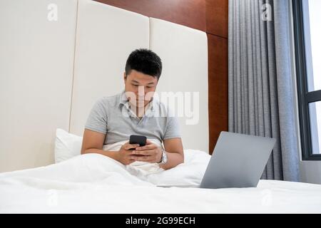 Controllare le e-mail sullo smartphone nella camera d'albergo Foto Stock