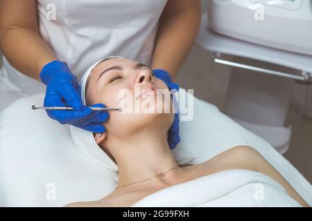 Estetista che utilizza un cucchiaio professionale a più fori per pulire viso e pori. Foto Stock