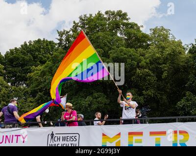 Berlino, Germania - 24 luglio 2021 - UN uomo fa ondate una bandiera arcobaleno su un camion alla manifestazione Christopher Street Day (CSD) a Berlino Foto Stock