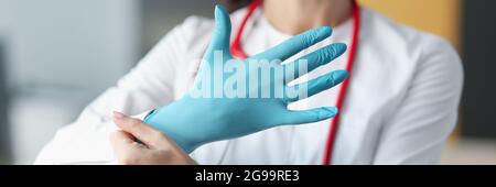 Un medico sorridente mette un guanto sulla sua mano Foto Stock