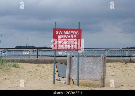 Cartello rosso con scritta bianca, attenzione alle forti correnti di marea sulla spiaggia di Shell Bay Ascolta Studland Poole Dorset UK Foto Stock