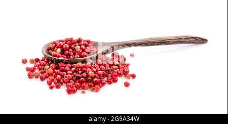 Rosa essiccati peperoni in cucchiaio di legno isolato su sfondo bianco Foto Stock