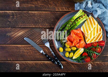 Insalata con asparagi, alloumi alla griglia, filetto di salmone, pomodori, rucola e olive verdi. Vista dall'alto Foto Stock