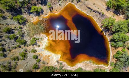 Lago rosso acido al posto della miniera di rame a cielo aperto abbandonata vicino a Kinousa, Cipro. Vista aerea direttamente dall'alto Foto Stock