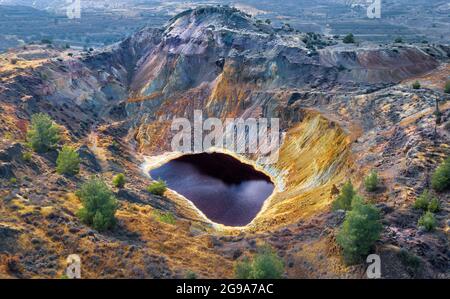 Lago rosso acido e rocce colorate nella miniera abbandonata vicino Kampia, Cipro. Quest'area presenta grandi quantità di minerale di rame e depositi di solfuro Foto Stock