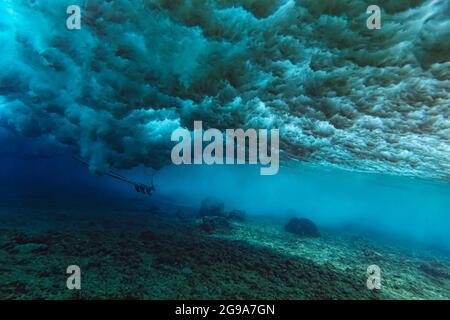 Vista sotto l'acqua dell'onda, surfista seduto su tavola da surf, scatto subacqueo Foto Stock