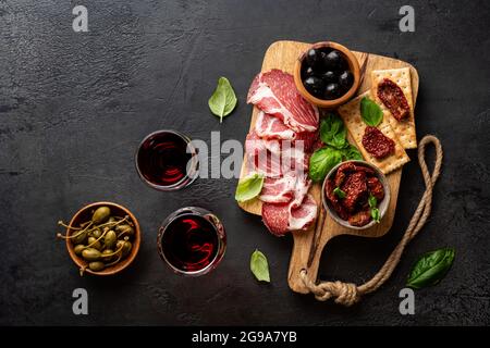 Antipasti con diversi antipasti, salumi, spuntini e vino rosso. Salsiccia, prosciutto, tapas, olive e cracker per un buffet party. Vista dall'alto, disposizione piatta Foto Stock