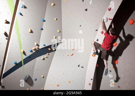 Bouldering scalatore al muro di arrampicata indoor a Londra Foto Stock