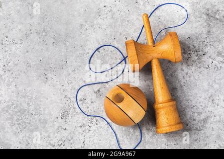 Classico giocattolo Kendama in legno con filettature blu su sfondo in cemento con spazio copia, vista dall'alto Foto Stock