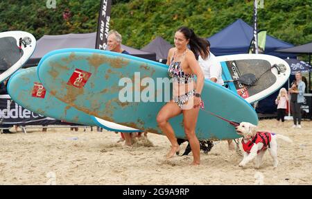 I concorrenti e i loro cani partecipano a Dogmasters, l'unico campionato del paese per il surf con i cani e il paddleboard, a Branksome Beach a Poole, Dorset. Data immagine: Domenica 25 luglio 2021. Foto Stock