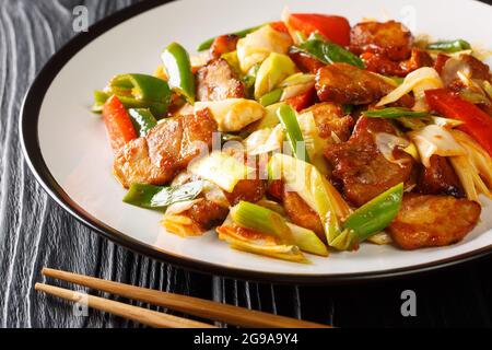 Due volte cotto maiale grasso tenero cotto in una salsa ricca e salsa gustosa e verdure chiodate nel piatto sul tavolo di legno. Orizzontale Foto Stock