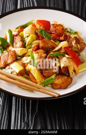 Il maiale cotto due volte o il maiale cotto doppio è un piatto cinese che include maiale e verdure saltate in padella nel piatto sul tavolo di legno. Verticale Foto Stock