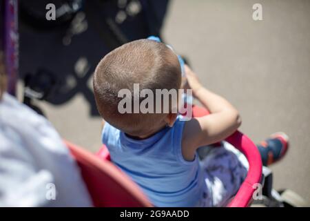 Bambino piccolo in passeggino. Cammina con il bambino al sole. Una giornata calda per il bambino. Testa del bambino. Foto Stock