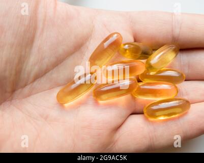 Capsule di gel omega-3 di olio di fegato di baccalà di tenuta a mano maschile primo piano. Capsule per la mano omega 3 o capsule di olio di pesce isolate su fondo bianco. Salute ca Foto Stock