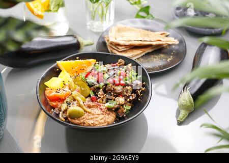 Humus con melanzane e insalata di olive. Cucina vegetariana. Un piatto colorato appetitoso. Fotografia culinaria, stile alimentare. Foto Stock