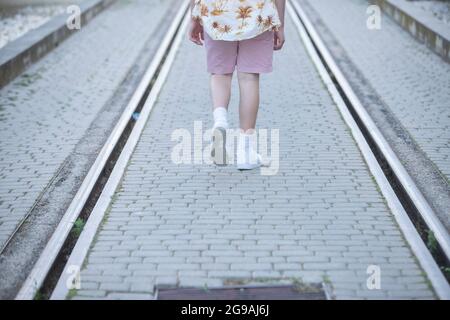 le gambe della ragazza adolescente che camminano tra le piste ferroviarie Foto Stock