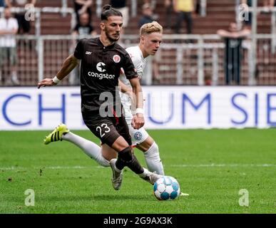 Amburgo, Germania. 25 luglio 2021. Calcio: 2 Bundesliga, FC St. Pauli - Holstein Kiel, giorno 1. Paqarada di San Pauli (l) e il Finn Porath di Kiel combattono per la palla. Credito: Axel Heimken/dpa - NOTA IMPORTANTE: In conformità con le norme del DFL Deutsche Fußball Liga e/o del DFB Deutscher Fußball-Bund, è vietato utilizzare o utilizzare fotografie scattate nello stadio e/o della partita sotto forma di sequenze fotografiche e/o serie fotografiche di tipo video./dpa/Alamy Live News Foto Stock