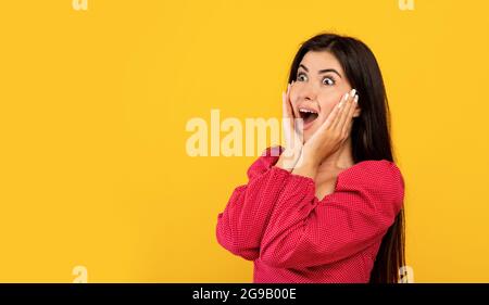 Vendita o promo concetto enorme. Donna armena sorpresa urlando, guardando lo spazio libero su sfondo giallo, panorama Foto Stock