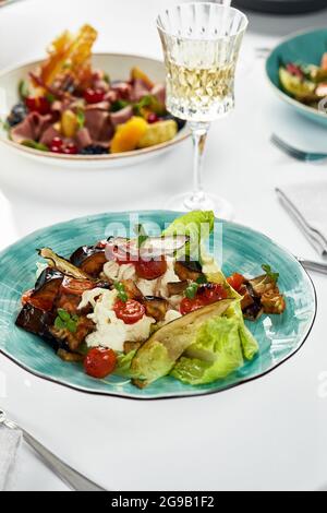 Insalata con melanzane al forno e ricotta, primo piano, sapore fresco di ricotta morbida con foglie di lattuga e melanzane cotte grossolanamente tritate Foto Stock