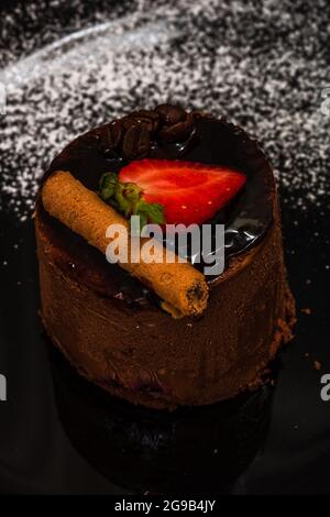 Un colpo verticale di torta di mousse al cioccolato con una fragola Foto Stock