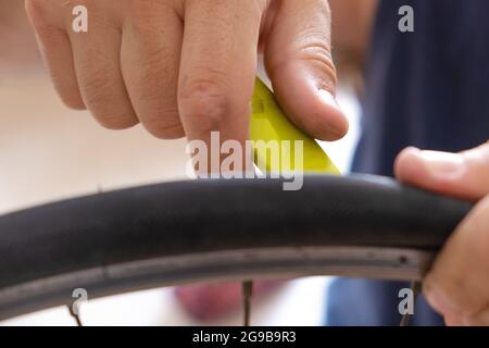 Primo piano delle mani di un uomo che ripara una ruota di bicicletta. Riparazione di biciclette e nuovo concetto di mobilità Foto Stock