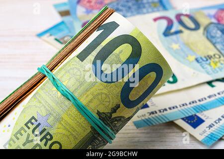 Rotolo di banconote da 100 euro contro un primo piano in valuta cartacea da 20 euro. Concetti di denaro, risparmio di denaro, contabilità di reddito e spese, conteggio di denaro Foto Stock