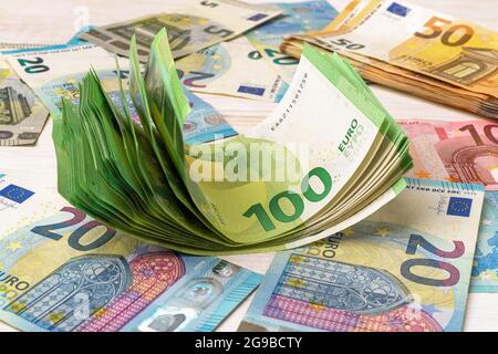 WAD di 100 banconote in euro su base di valuta cartacea in euro. Concetti di contabilità di reddito e spese, risparmio di cassa, contando denaro e ricchezza. Foto Stock