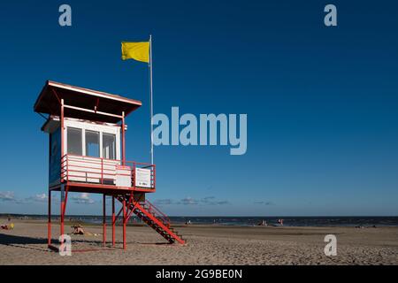 Pärnu, Estonia - 11 luglio 2021: La torre del bagnino G4S con bandiera gialla indica che il nuoto è pericoloso per i nuotatori poveri. Foto Stock