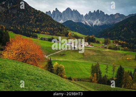 Uno dei luoghi alpini più belli del mondo, Santa Maddalena villaggio con splendide montagne dolomitiche sullo sfondo, Val di Funes valle, tre Foto Stock