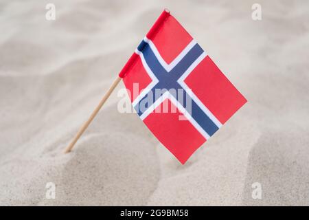 Bandiera della Norvegia su fondo sabbioso. Bandiera norvegese sventolando nel vento sulla spiaggia estiva Foto Stock